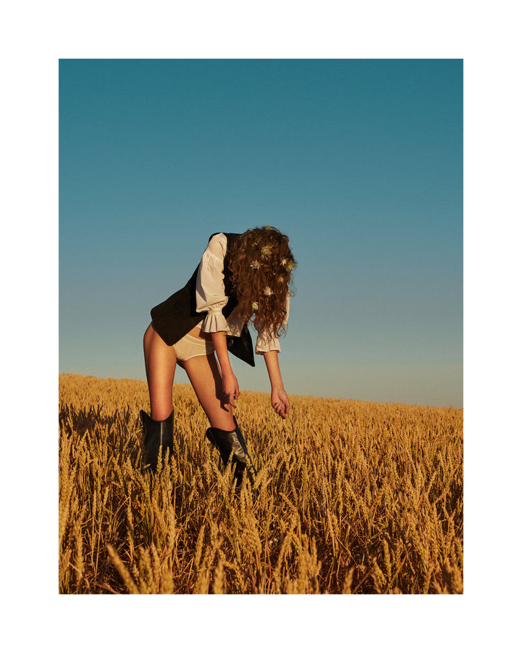 Woman with har full of thistles photographed on a field of wheats.