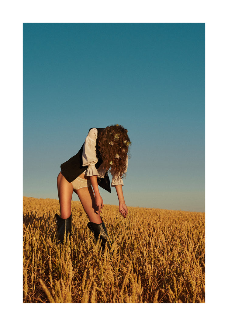 Woman with har full of thistles photographed on a field of wheats.