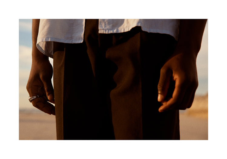 Man wearing white shirt and brown slacks.