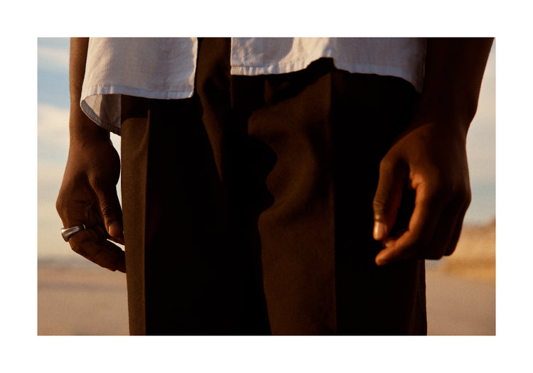 Man wearing white shirt and brown slacks.