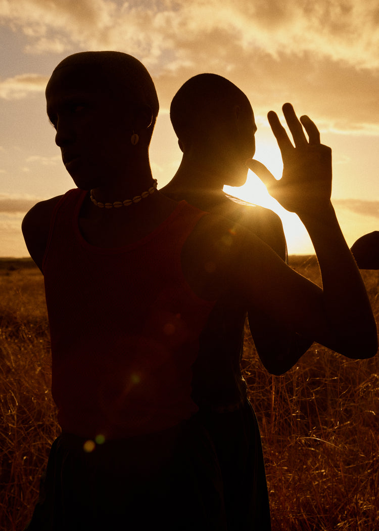 Two brothers standing back-to-back on an open field in the gazing sun.