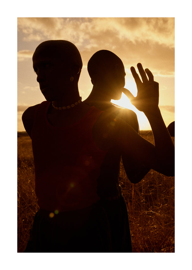 Two brothers standing back-to-back on an open field in the gazing sun.