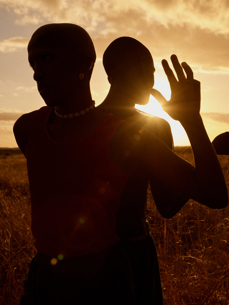 Two brothers standing back-to-back on an open field in the gazing sun.