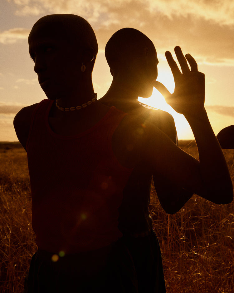Two brothers standing back-to-back on an open field in the gazing sun.