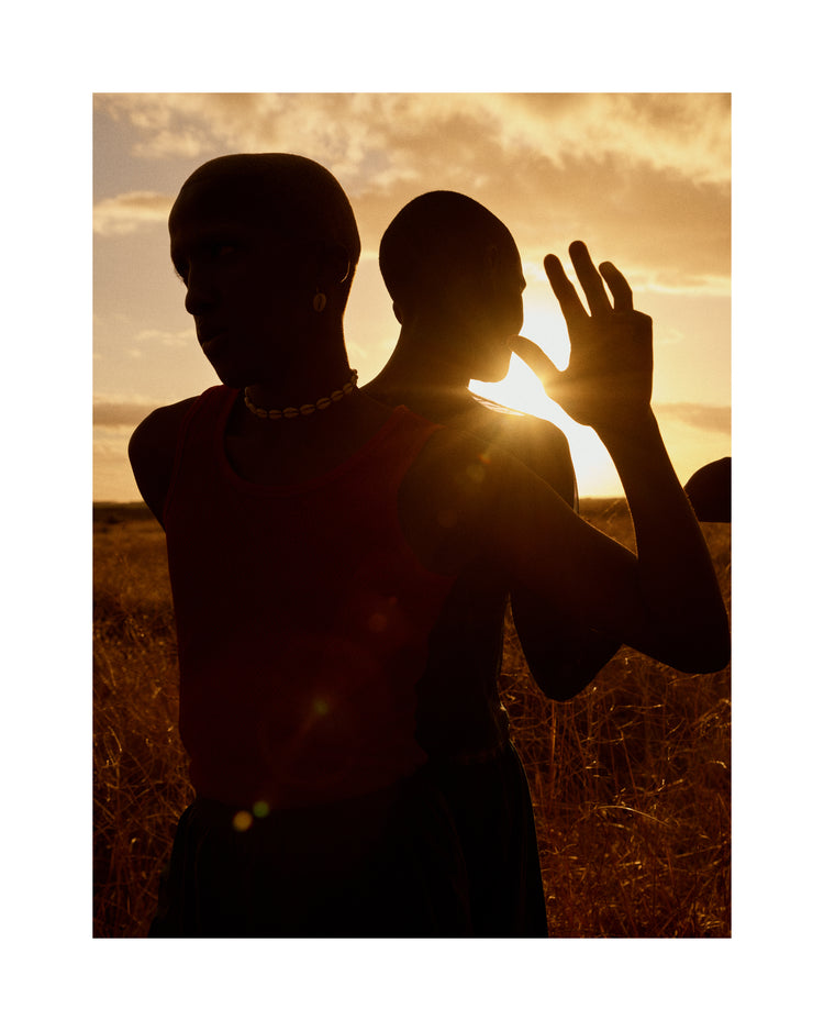 Two brothers standing back-to-back on an open field in the gazing sun.