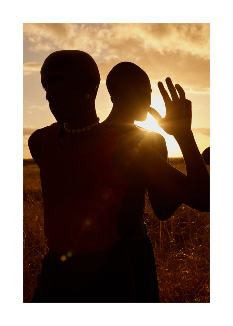 Two brothers standing back-to-back on an open field in the gazing sun.