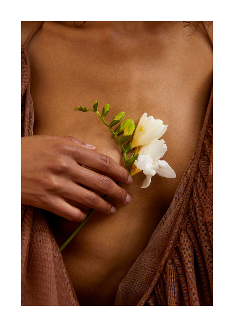 A woman wearing a low-cut dress covering her chest with a white flower.