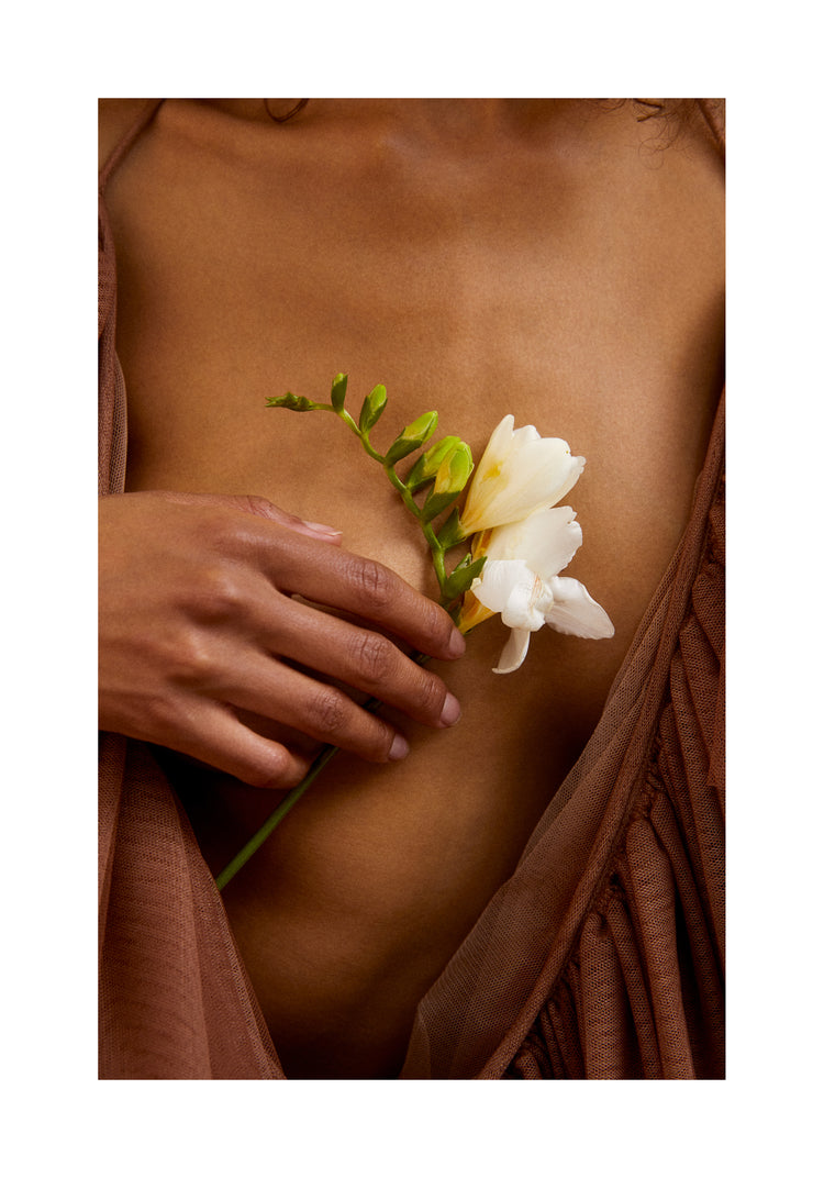 A woman wearing a low-cut dress covering her chest with a white flower.
