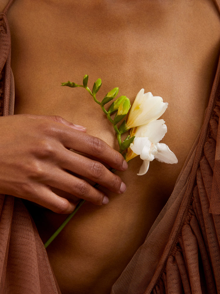 A woman wearing a low-cut dress covering her chest with a white flower.
