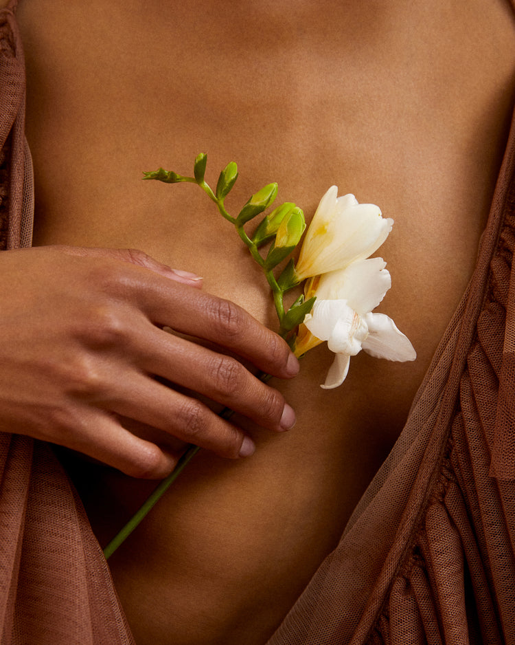 A woman wearing a low-cut dress covering her chest with a white flower.