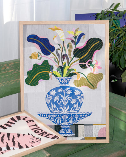 The Vase Poster features a framed painting of a blue vase with colorful leaves and flowers on a green bench, capturing the charm of traditional Persian and Indian art. Beside it is an abstract shapes artwork, with a background plant adding an organic touch.