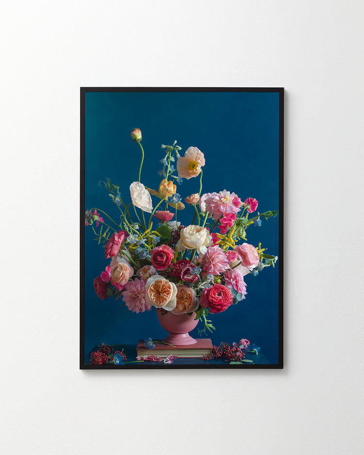 The Pink Kiss Poster features a framed artwork of a romantic bouquet with assorted flowers, including pink and white roses, set against a deep blue background. An elegant arrangement in a pink vase with some flowers spilling over the edge.