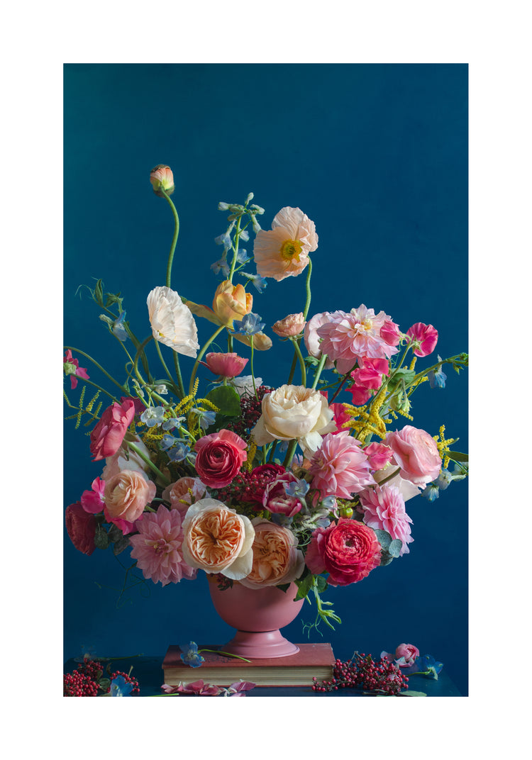 The Pink Kiss Poster showcases a vibrant floral arrangement in a pink vase with a deep blue backdrop, highlighting romantic roses, poppies, and dahlias in pink, red, and white hues with interspersed green foliage for an elegant style.