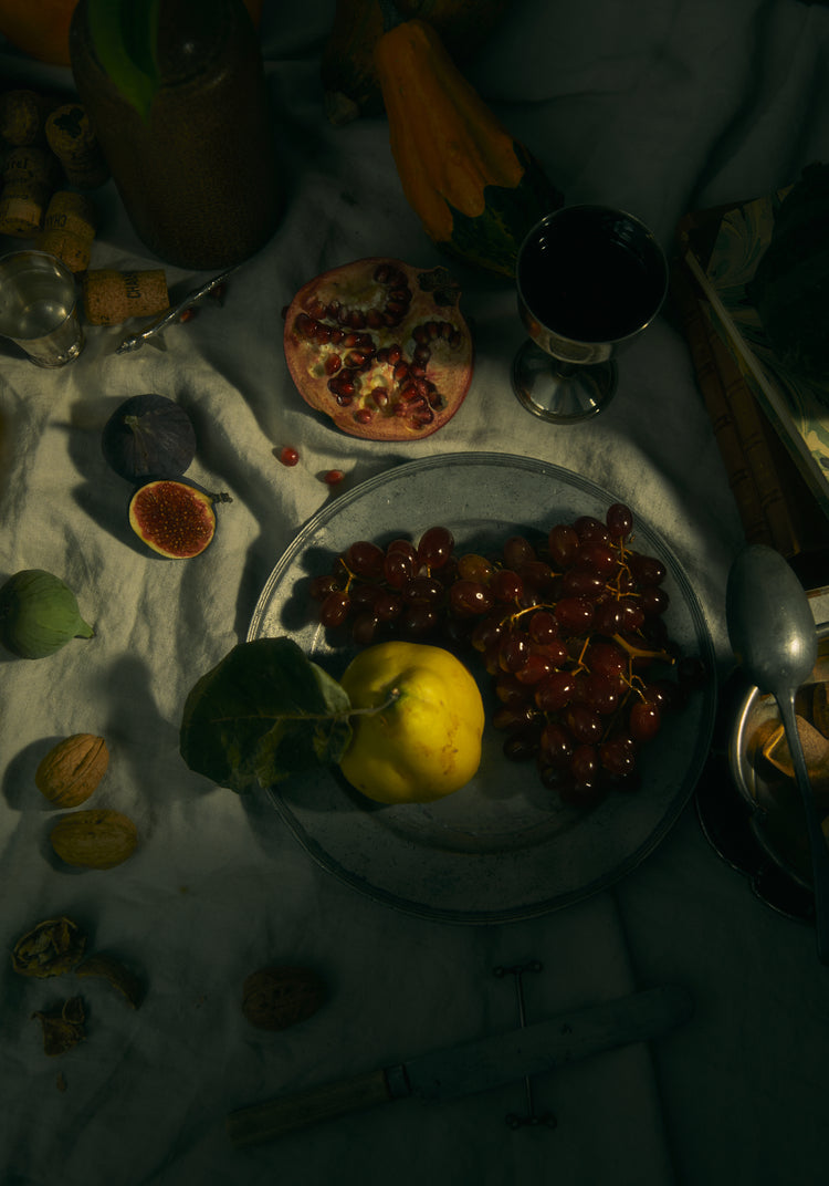Still life photograph of a sheet with different fruits and objects on it.
