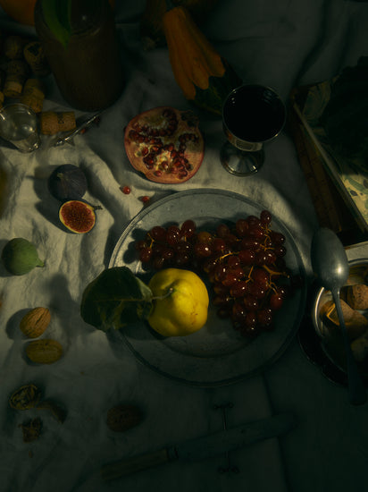 Still life photograph of a sheet with different fruits and objects on it.