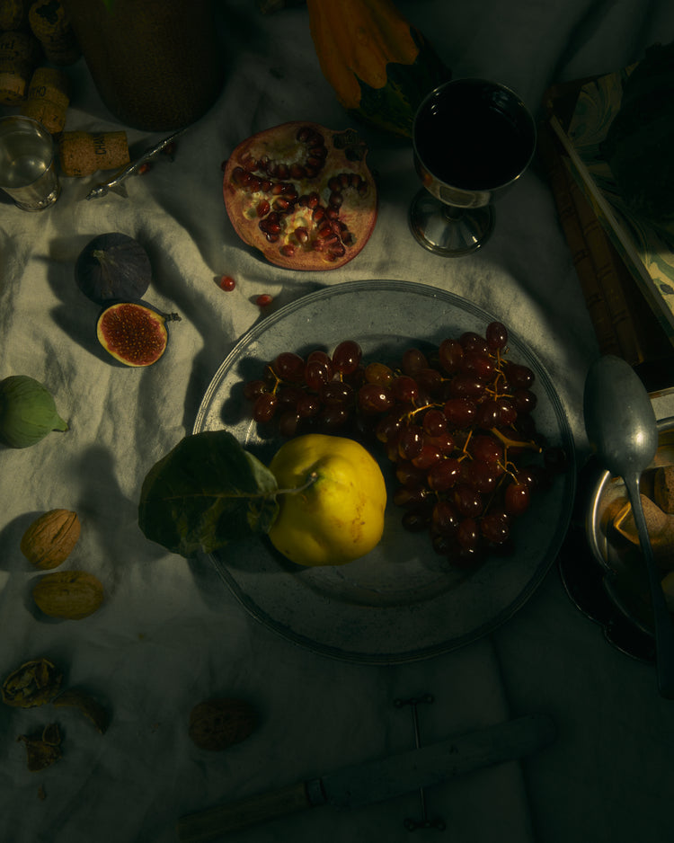 Still life photograph of a sheet with different fruits and objects on it.