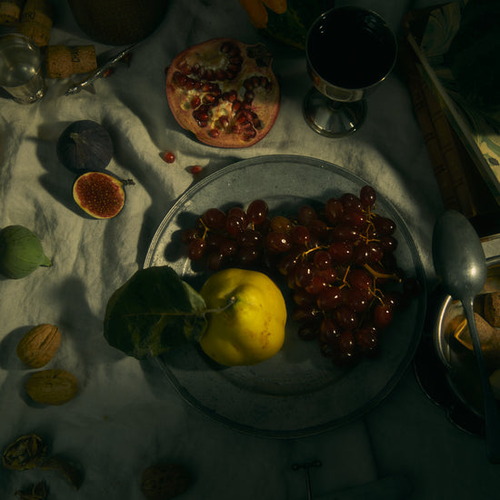 Still life photograph of a sheet with different fruits and objects on it.