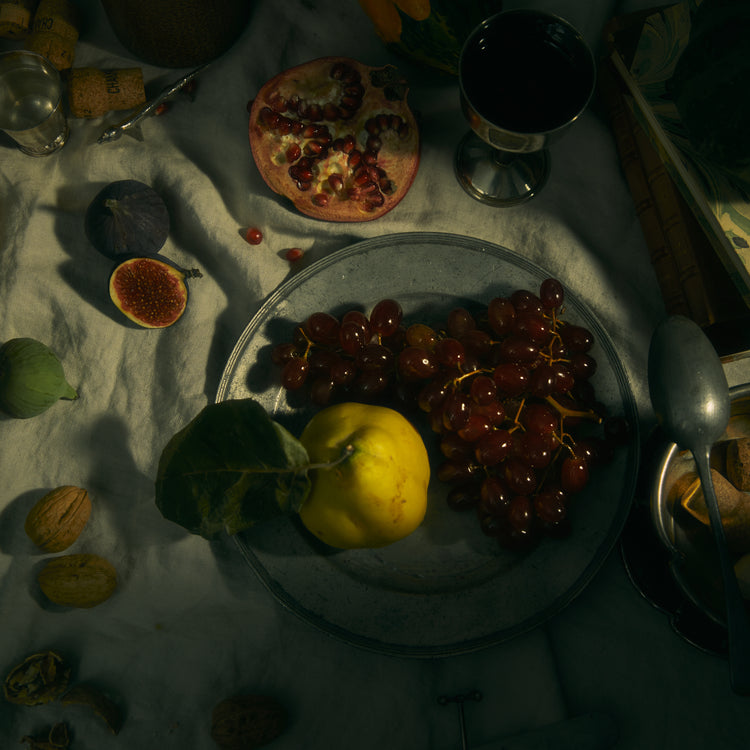 Still life photograph of a sheet with different fruits and objects on it.