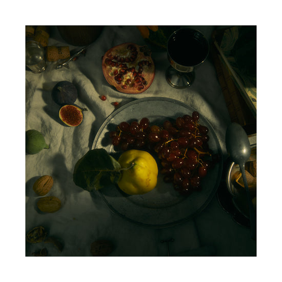 Still life photograph of a sheet with different fruits and objects on it.