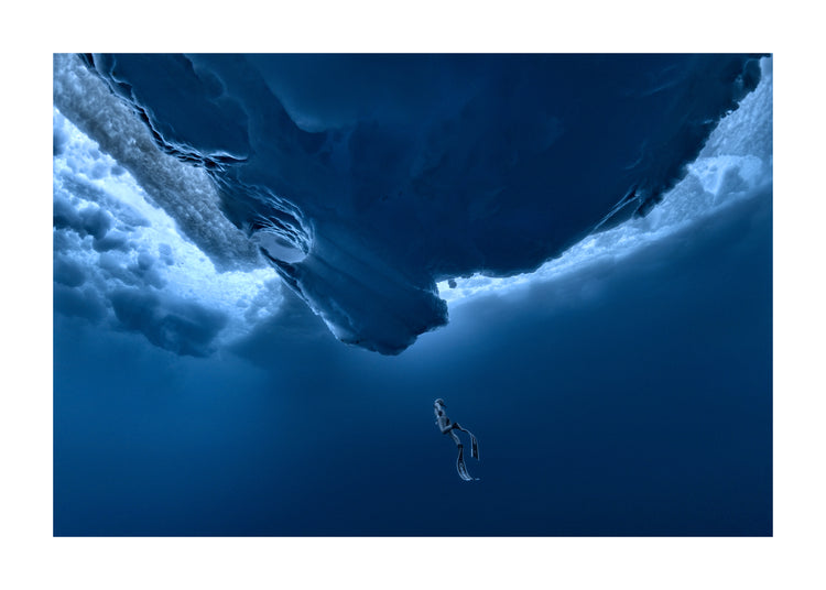 Lonely free-diver swimming towards a surface covered in ice.