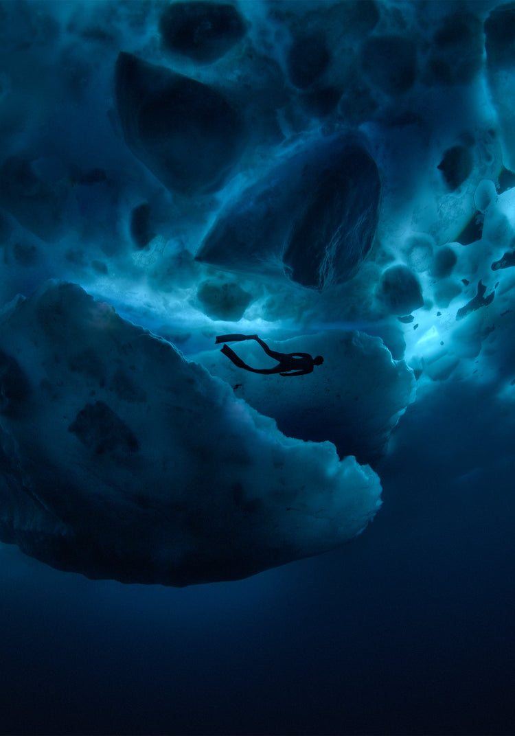 Diver swimming underneath ice bergs.