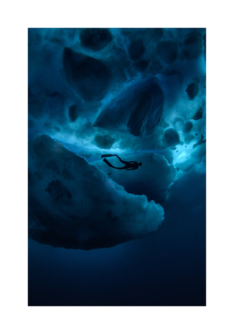 Diver swimming underneath ice bergs.