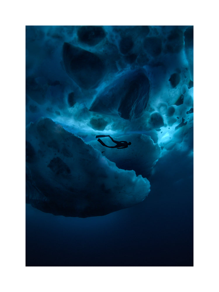 Diver swimming underneath ice bergs.