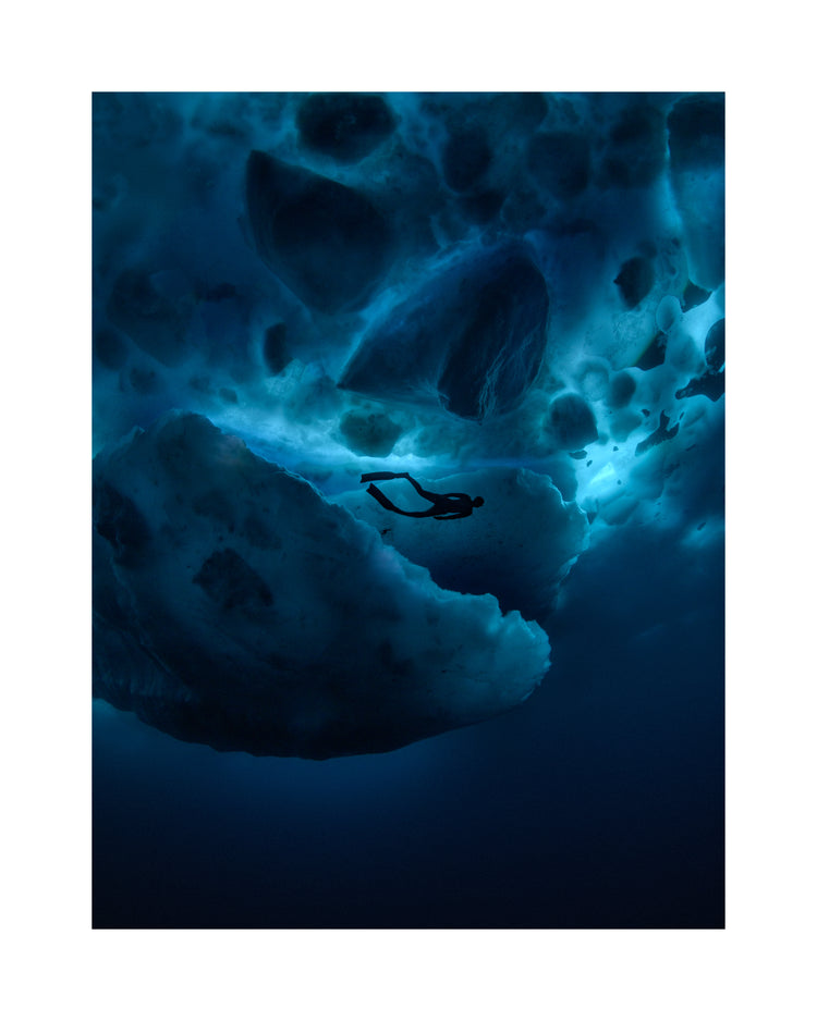 Diver swimming underneath ice bergs.