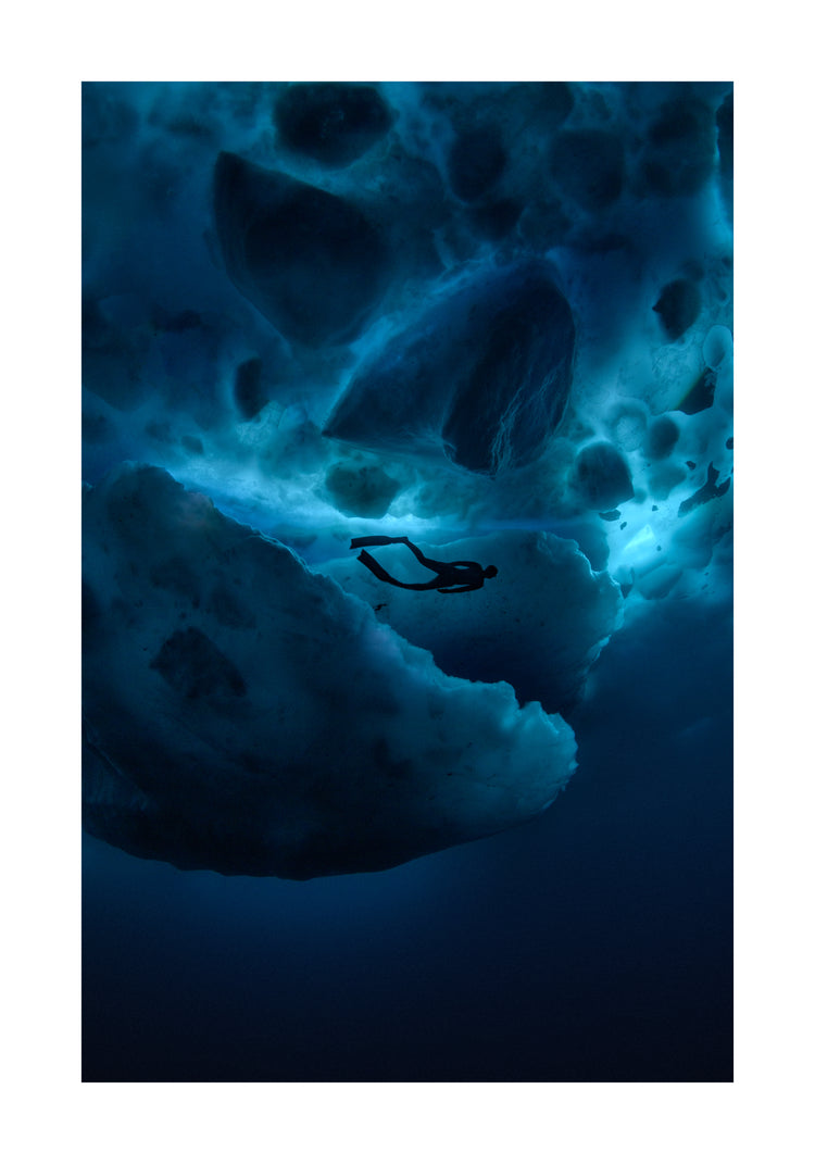 Diver swimming underneath ice bergs.