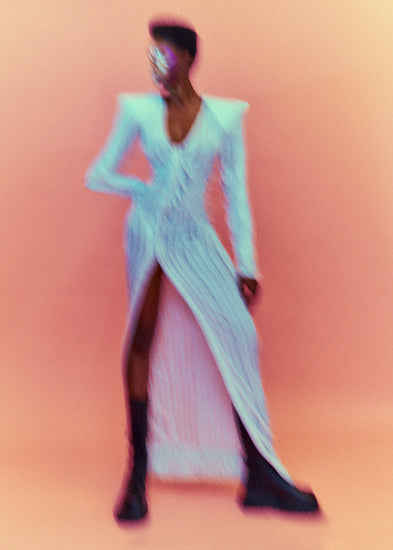 A blurry poster of a woman in a white dress in front of a peach pink background.