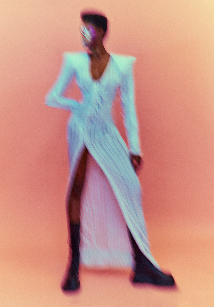 A blurry poster of a woman in a white dress in front of a peach pink background.