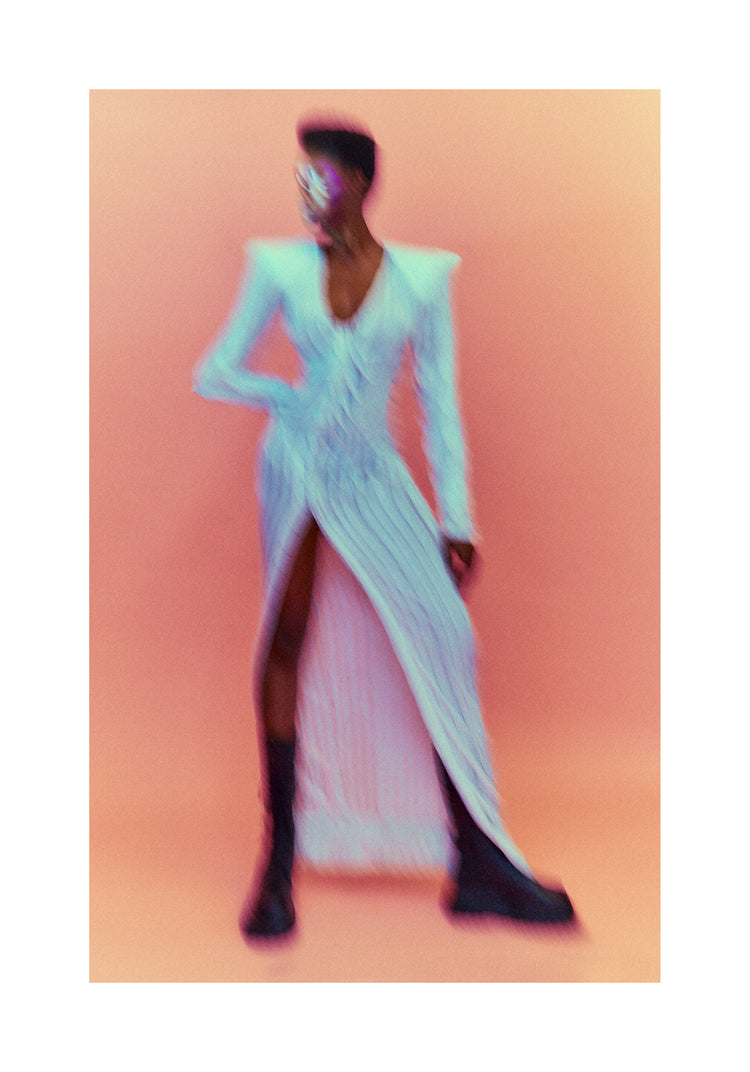 A blurry poster of a woman in a white dress in front of a peach pink background.