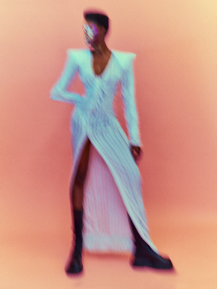 A blurry poster of a woman in a white dress in front of a peach pink background.