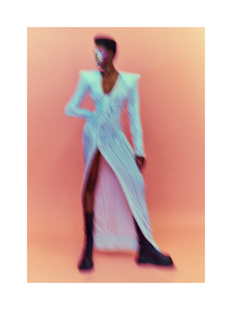 A blurry poster of a woman in a white dress in front of a peach pink background.