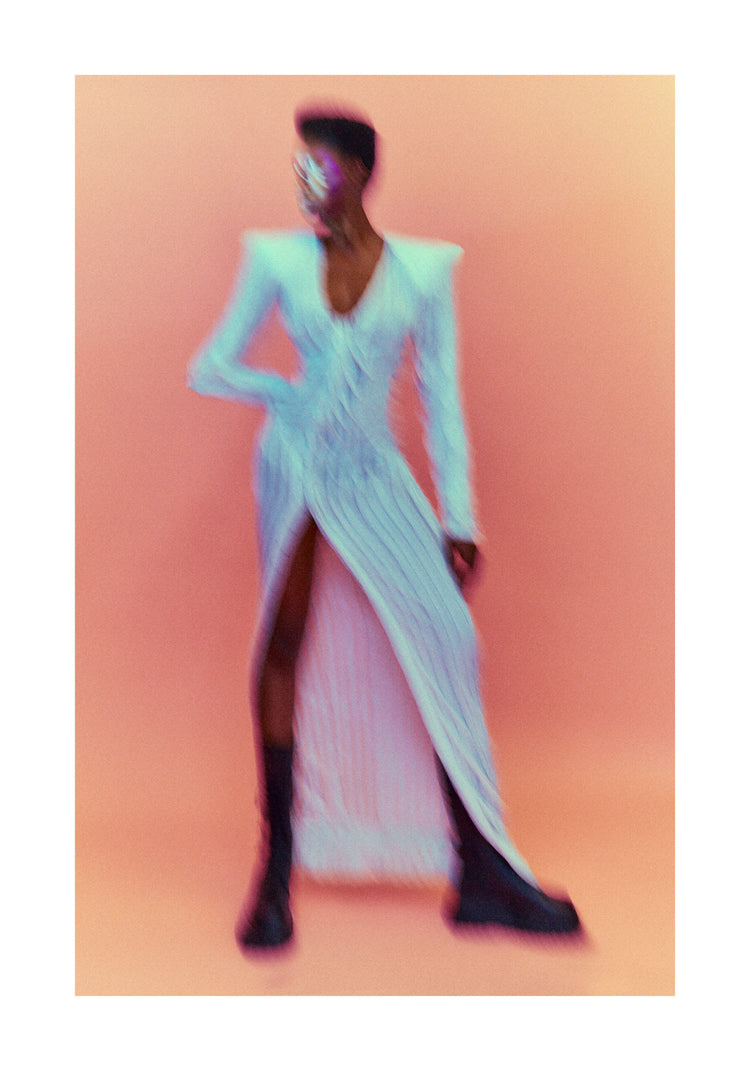 A blurry poster of a woman in a white dress in front of a peach pink background.