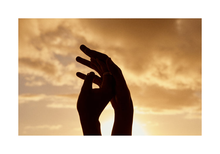 Hands grasping for each other in front of a crimson sky.