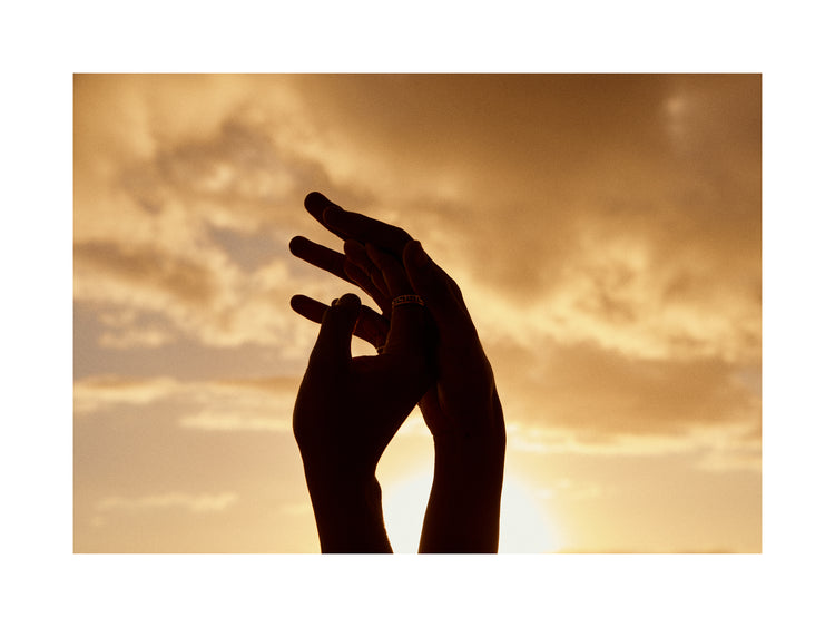 Hands grasping for each other in front of a crimson sky.