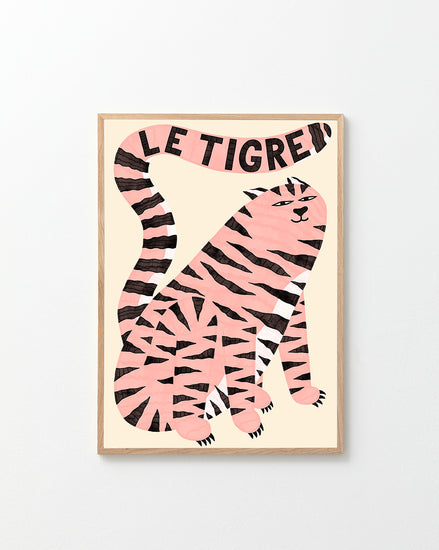 The Le Tigre White Poster showcases a stylish pink tiger with black stripes on a beige background. Its tail artistically spells LE TIGRE above, all enclosed in an elegant light wood frame, creating a captivating art piece of wild sophistication.