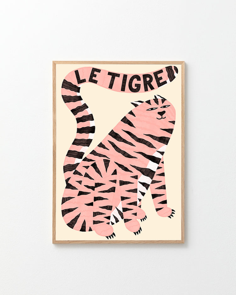 The Le Tigre White Poster showcases a stylish pink tiger with black stripes on a beige background. Its tail artistically spells LE TIGRE above, all enclosed in an elegant light wood frame, creating a captivating art piece of wild sophistication.