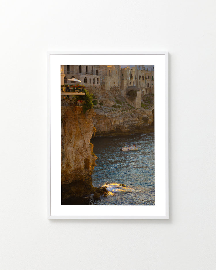 Sun setting over an Italian lake surrounded by houses on high cliffs.