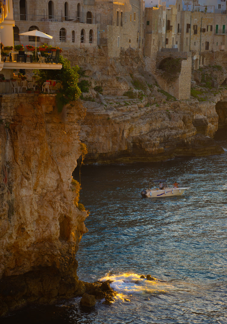 Sun setting over an Italian lake surrounded by houses on high cliffs.