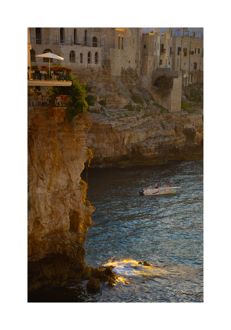 Sun setting over an Italian lake surrounded by houses on high cliffs.