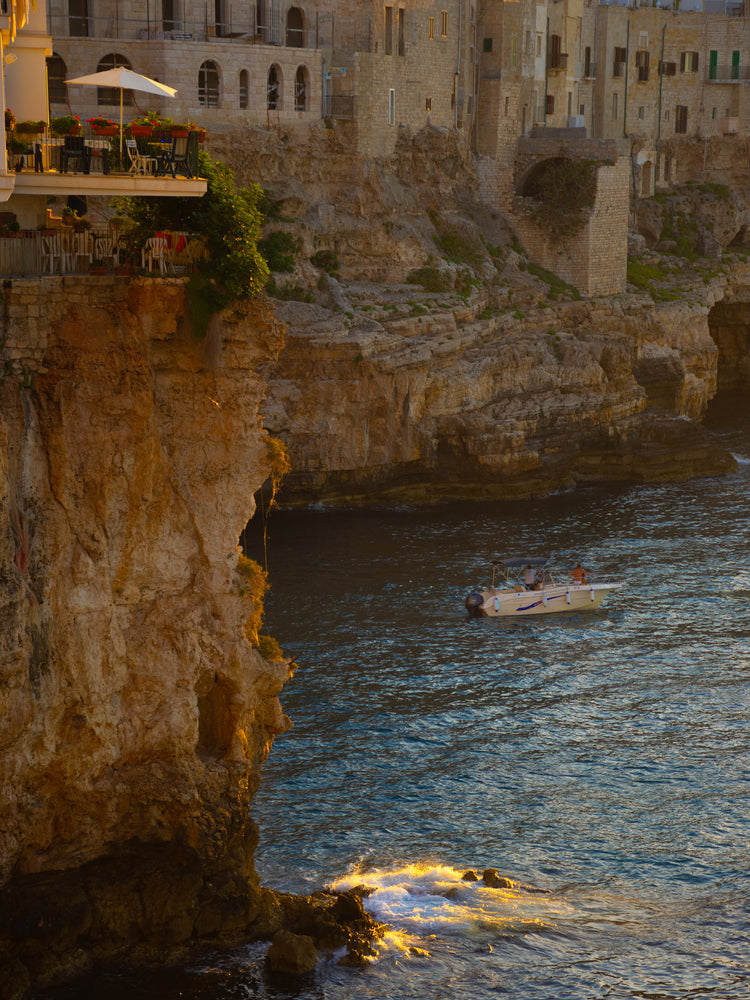 Sun setting over an Italian lake surrounded by houses on high cliffs.