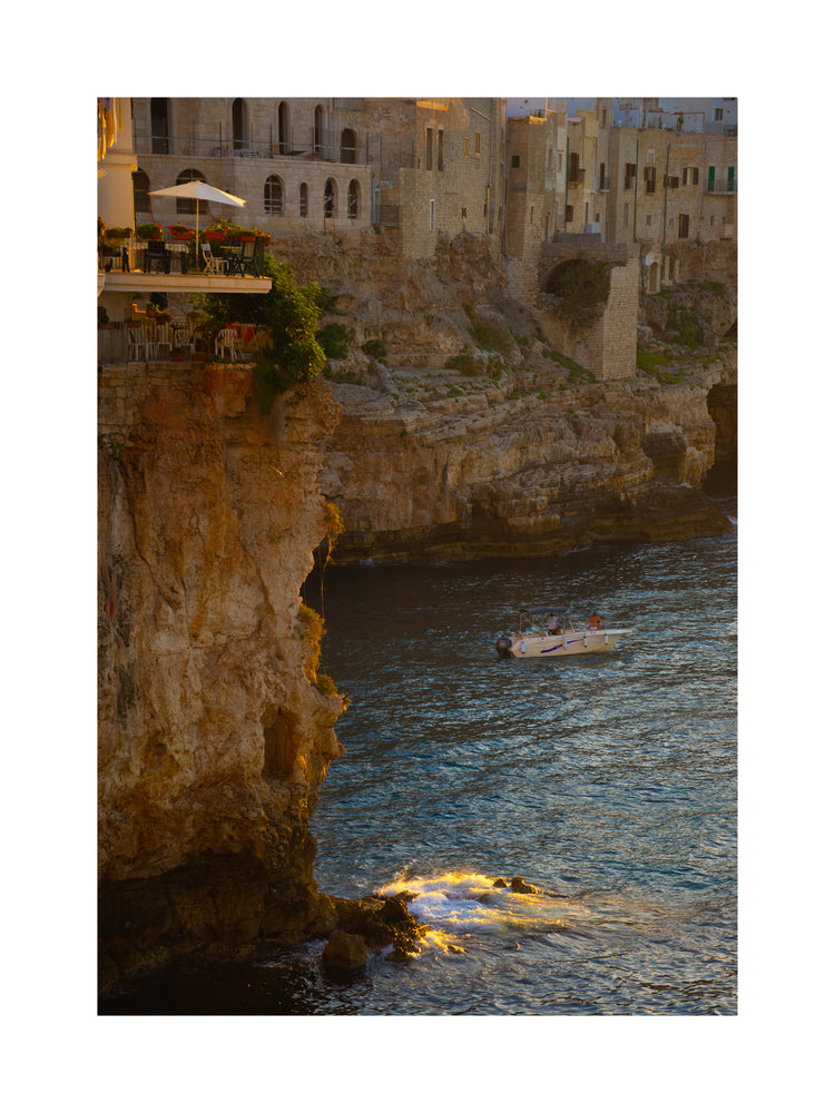 Sun setting over an Italian lake surrounded by houses on high cliffs.