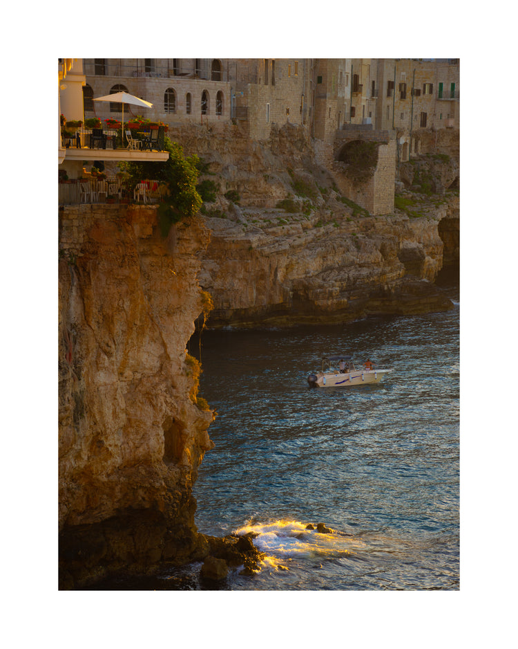 Sun setting over an Italian lake surrounded by houses on high cliffs.