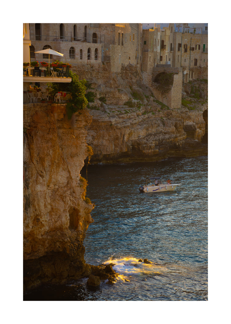Sun setting over an Italian lake surrounded by houses on high cliffs.