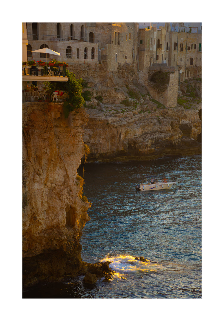 Sun setting over an Italian lake surrounded by houses on high cliffs.