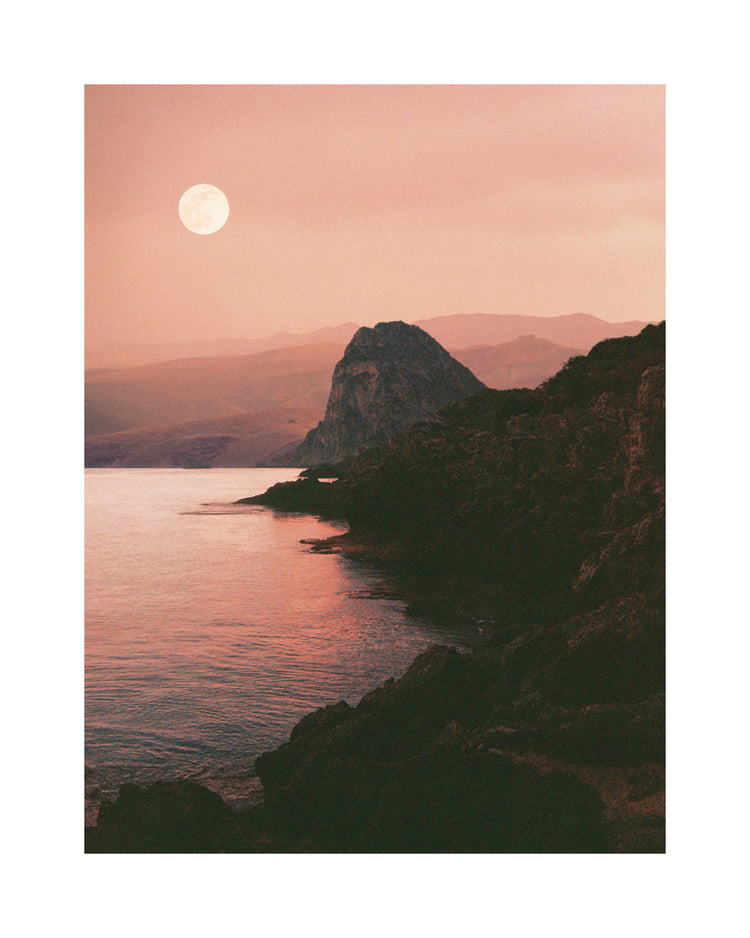 Full moon shining bright over the coastline set in a mountain scenery.