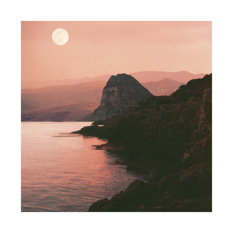 Full moon shining bright over the coastline set in a mountain scenery.