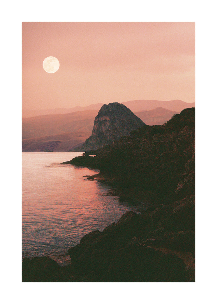 Full moon shining bright over the coastline set in a mountain scenery.